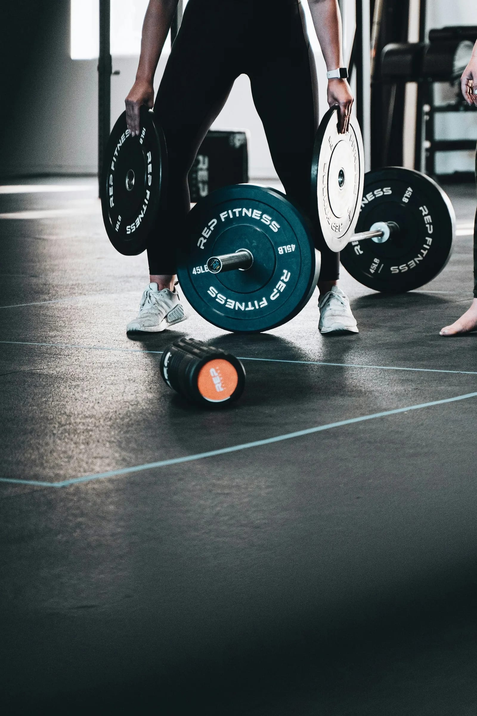 A foam roller and dumbbells laid out on the gym floor